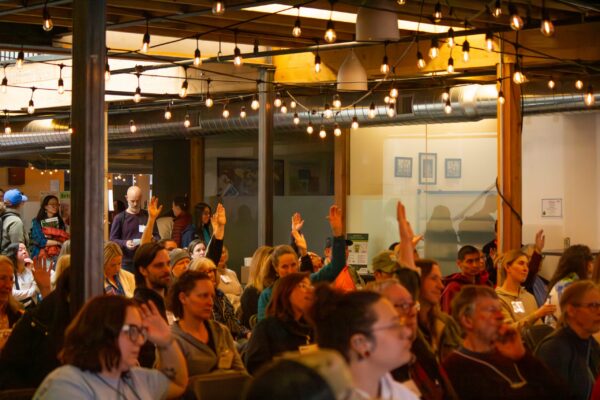 People raising their hands at symposium 2026