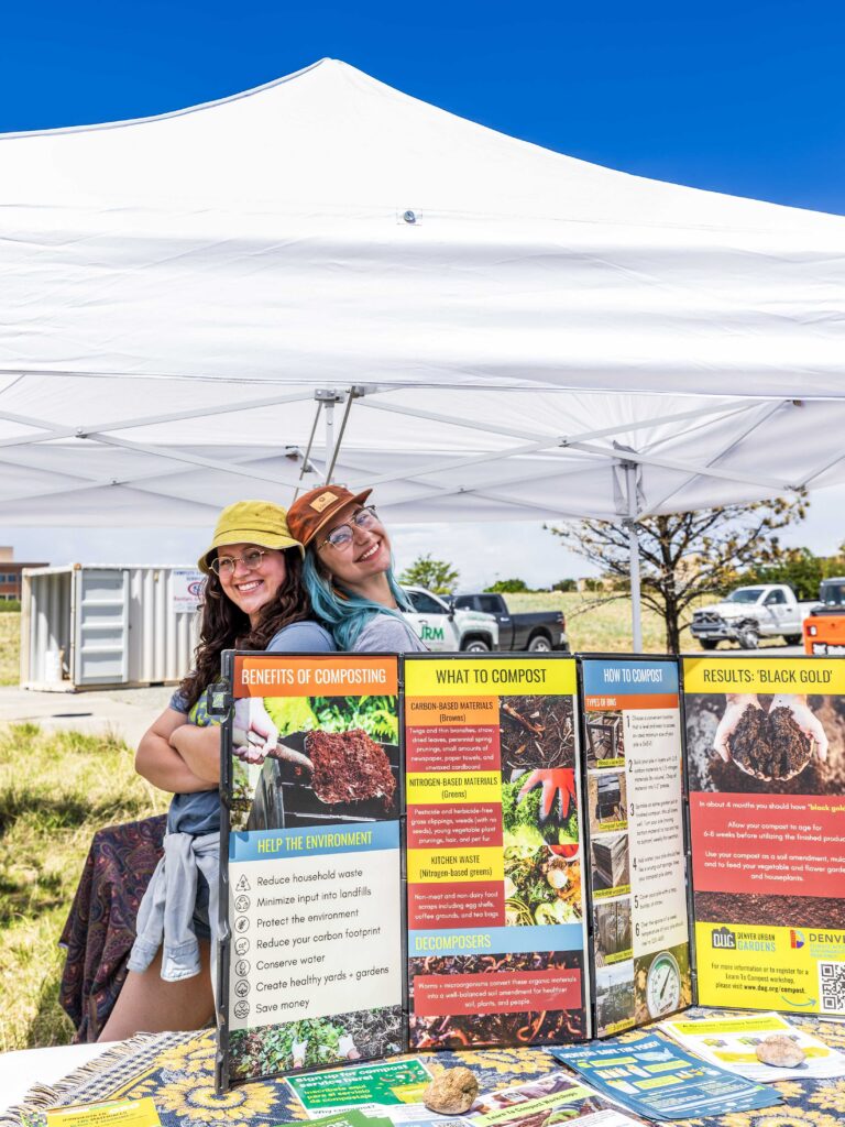 two people smiling behind table with compost information