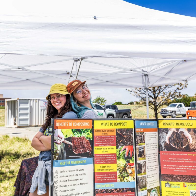 two people smiling behind table with compost information