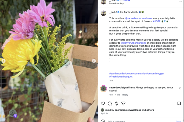 Bouquet of pink, yellow, and purple flowers in a white paper bag outdoors, with a cardboard box nearby.